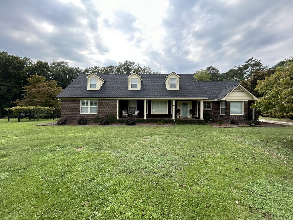 item_0a9c5983-57f3-41c6-a511-f50f3092d0e4 Large single-story brick home with a freshly installed dark gray shingle roof in Myrtle Beach, SC