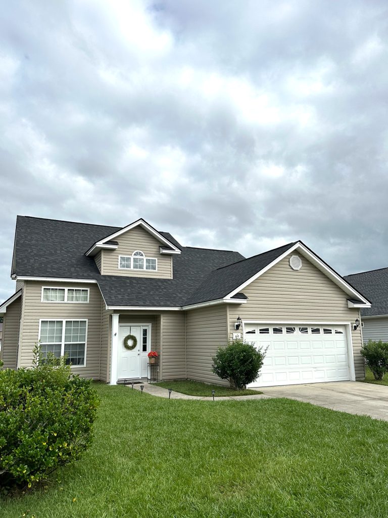 item_6245d5c4-ea0d-447b-a20f-096090b26135 Two-story tan home with new dark gray shingle roof and attached garage in Myrtle Beach, SC