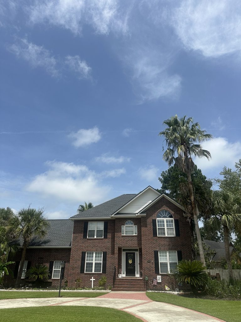 Large brick two-story home with palm trees and a newly installed shingle roof in Charleston, SC