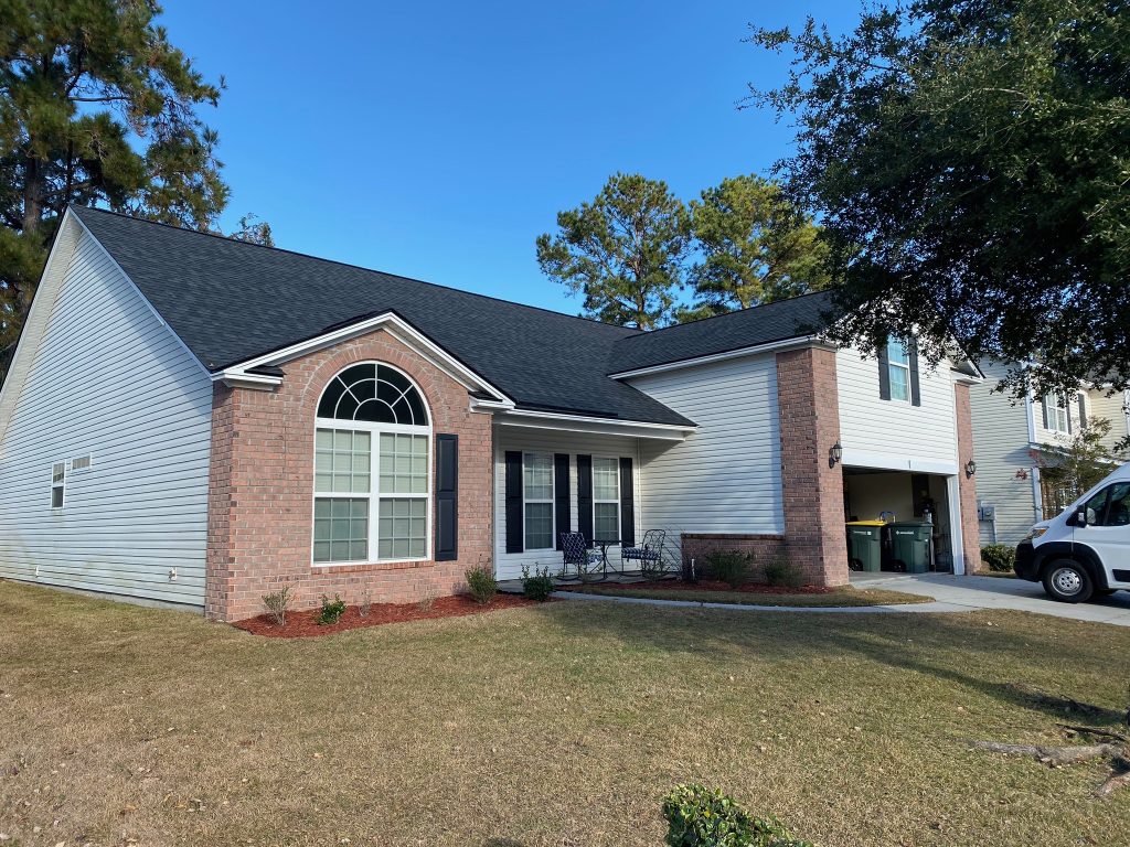 item_8d1689ee-b17f-4d35-87cc-9363661007c9 Single-story home with a new dark gray shingle roof under a clear blue sky in Savannah, GA