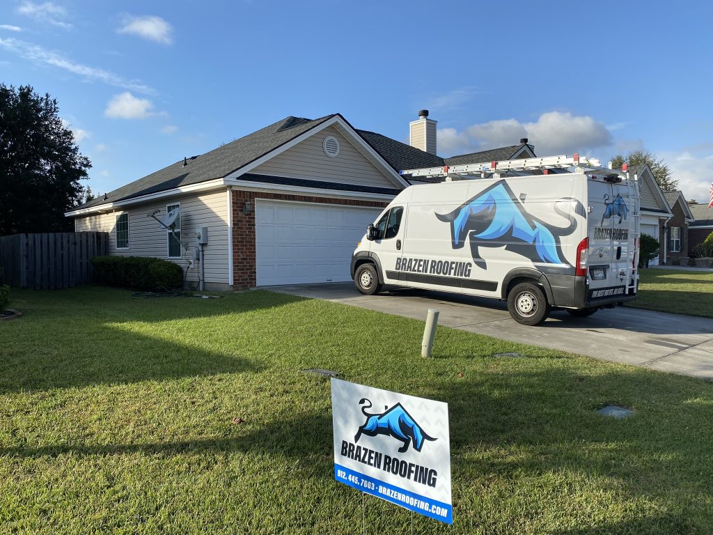 item_cad825dd-7bf1-4970-a4d6-73329fb1871a Tan single-story home with a Brazen Roofing service van and yard sign after a roof installation in Savannah, GA