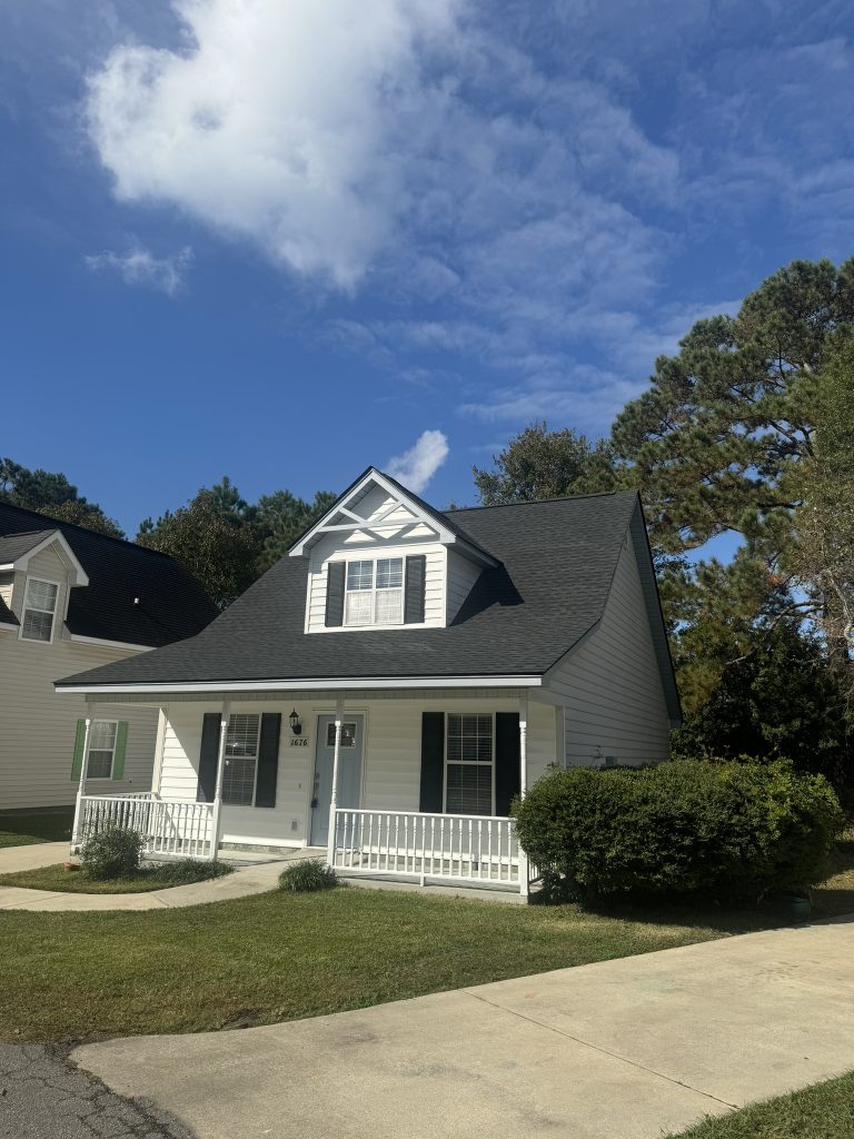 item_ecb0290b-c6a9-4b87-be30-d7e2e30b9f4c Gray-tan two-story home with dormer windows and a newly installed shingle roof in Myrtle Beach, SC