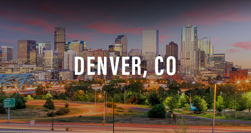 Dusk skyline view of Denver, CO with city lights and highway traffic trails