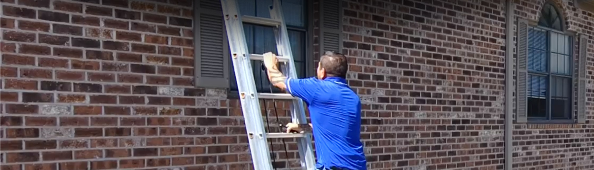 Brazen Roofing technician setting up a ladder against a historic brick home in Charleston, SC