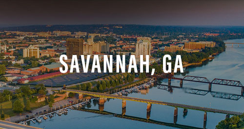 Aerial dusk view of the Savannah, GA riverfront skyline with bridge over the Savannah River