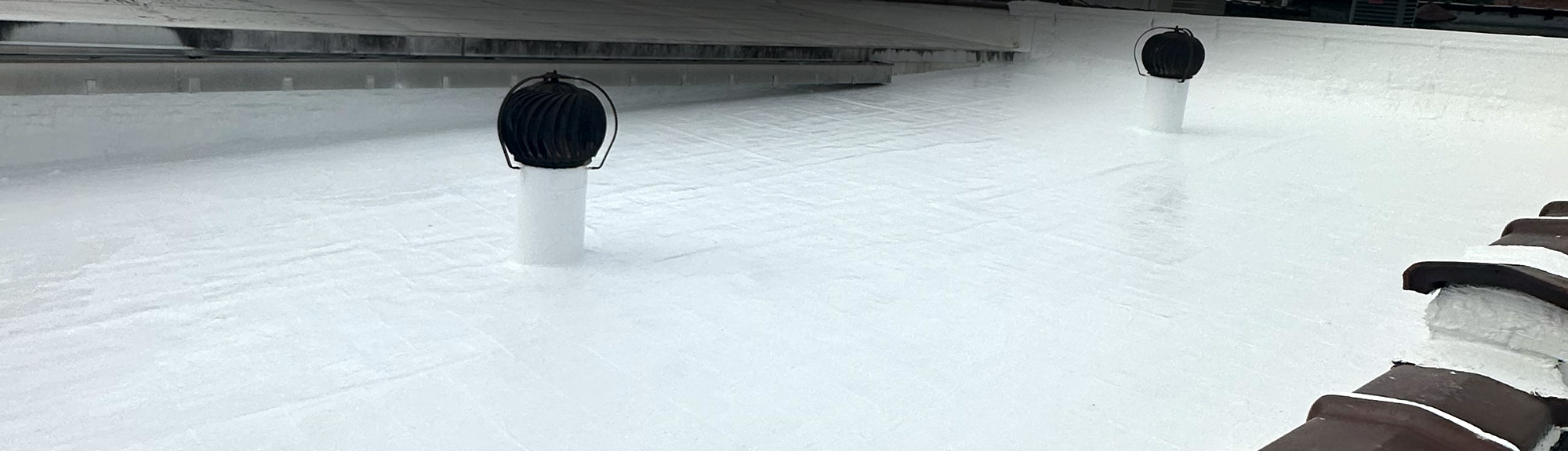 White reflective roof coating applied to a commercial flat roof in the Denver, CO area