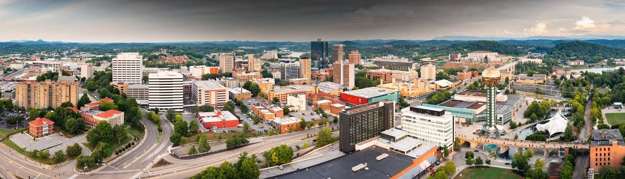 Aerial daytime view of downtown Knoxville, TN with a storm rolling in, home base for the roofing company Knoxville TN homeowners trust